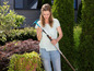 Een vrouw houdt een tuingereedschap vast in haar tuin.