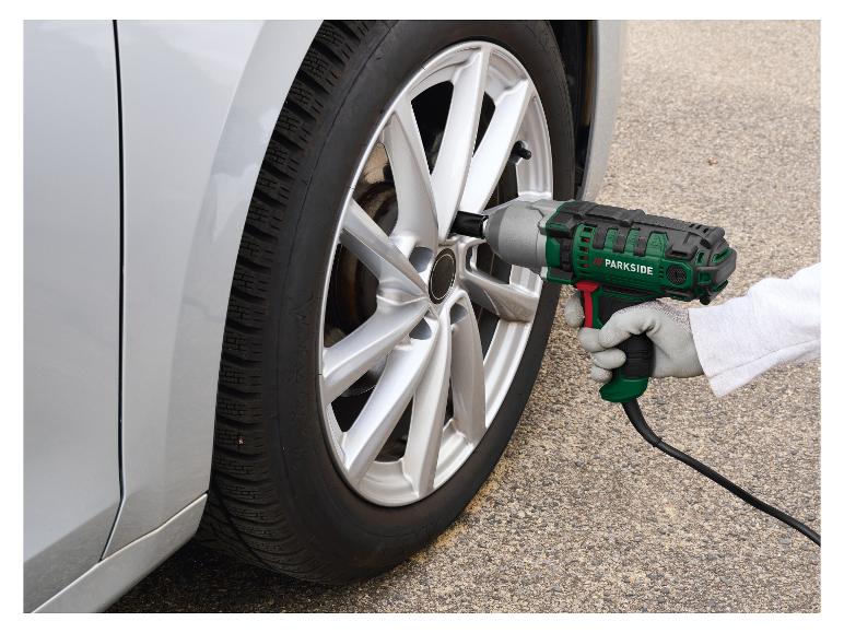 Persoon gebruikt een elektrische slagmoersleutel om een autoband te verwisselen.