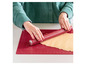 Een rood deegroller op een rode bakmat met een deeg er op.
