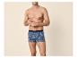 Man zonder shirt in boxershorts met palmboom- en ananasprint.