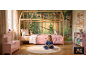 Meisje leest in een bos-thema slaapkamer met houten bed, roze beddengoed en opbergruimte.