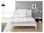 Bed met wit beddengoed en dekbed in een moderne slaapkamer.