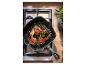 SILVERCREST® gietijzeren grillpan met lamskoteletten op het fornuis.