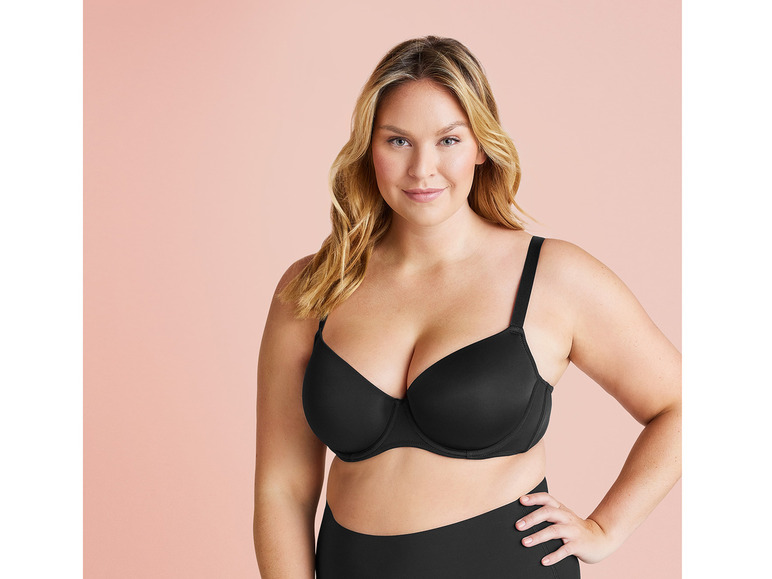 Een vrouw draagt een zwarte bh en een zwarte broek.