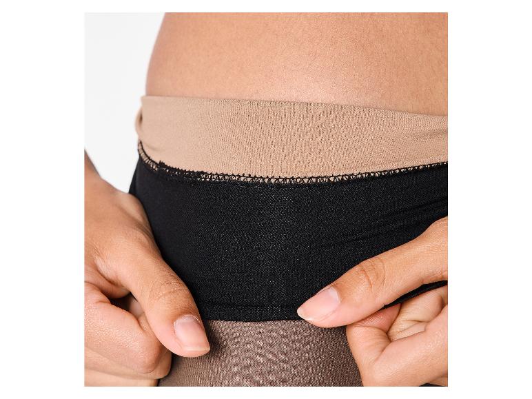 Vrouwenhand past zwarte panty met beige tailleband aan.