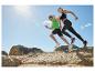 Twee atleten rennen over rotsen onder een blauwe lucht, in sportkleding en hardloopschoenen.