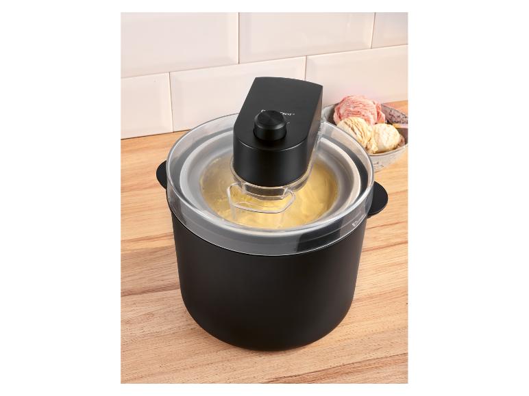 Zwarte ijsmachine met geel ijs en een kom met ijs op de achtergrond.