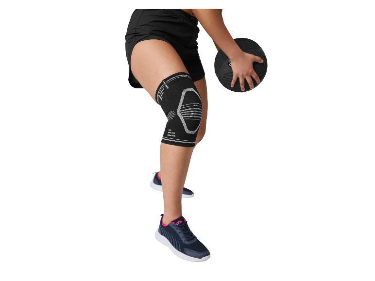 Persoon met zwarte kniebrace en zwarte shorts, houdt een zwarte medicijnbal vast.