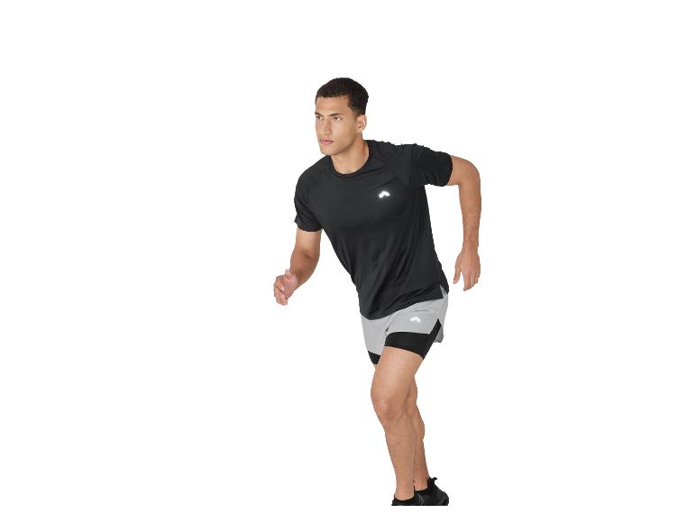 Man in zwart sportshirt en grijze shorts rent op een witte achtergrond.