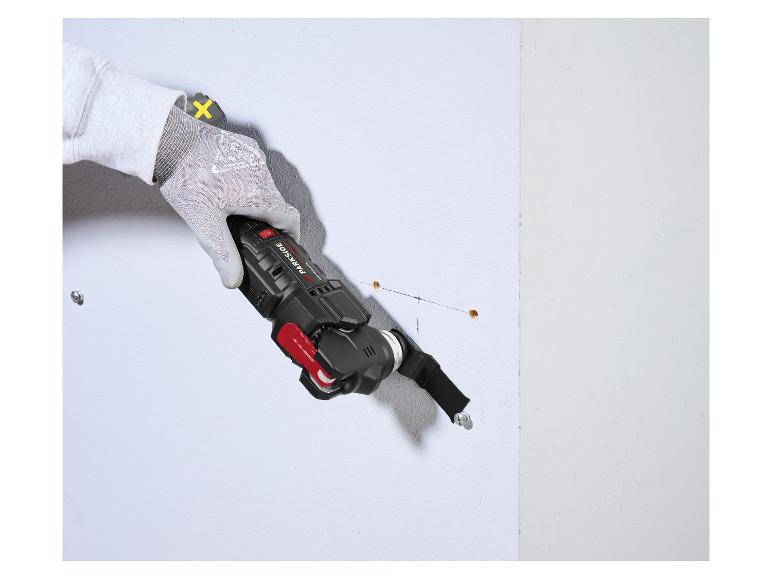Hand in een werkhandschoen die een multitool gebruikt om in een muur te zagen.