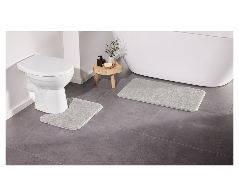 Twee badmatten in een badkamer, een voor de toilet en een voor de badkuip.