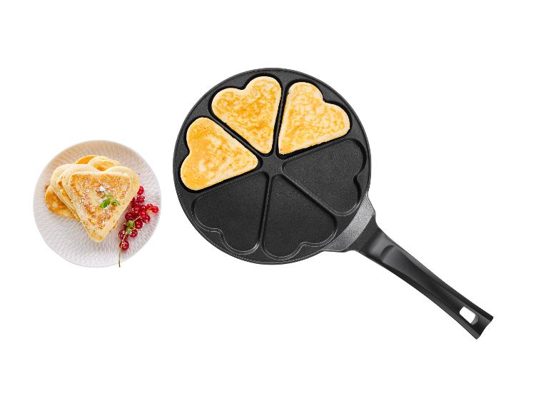 Pannenkoeken in hartvorm in een pan en op een bord.