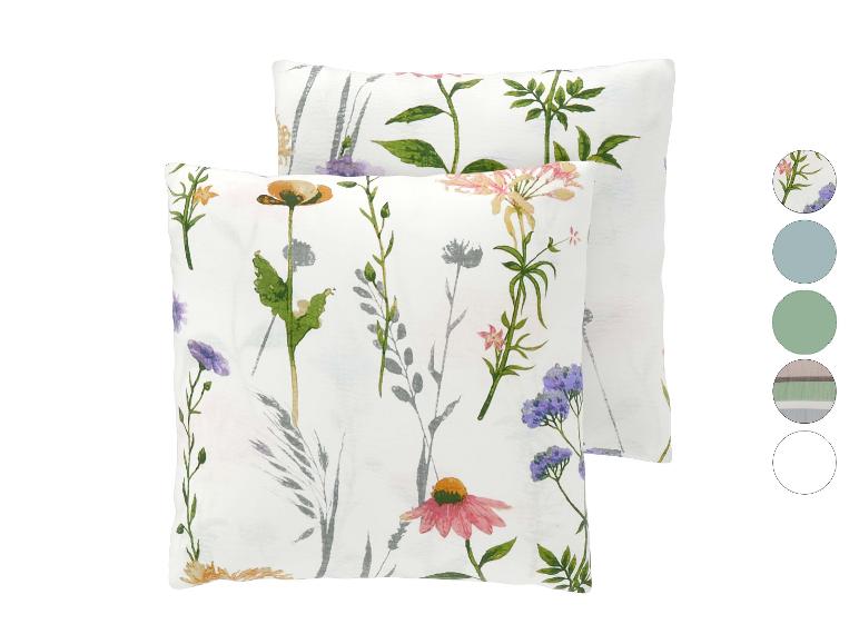 Twee witte kussens met een kleurrijk bloemenpatroon, met kleurstalen rechts.