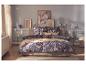 Slaapkamer met beddengoed met bloemenprint en een beige plaid op het bed.
