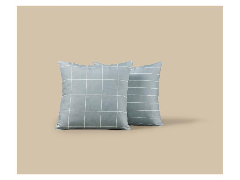 Twee blauwe geruite kussens op een beige achtergrond.