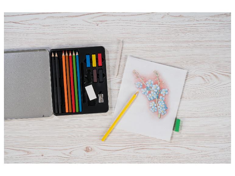 Kunstset met kleurpotloden, pastels en een bloemenschets op een houten tafel.