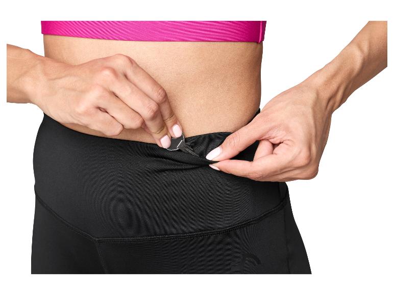 Vrouw stopt een sleutel in de zak van een zwarte sportlegging.