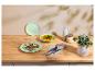 Houten tafel met een vlees- en saladeschotel, een kom soep, bestek en een plant.