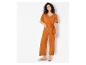 Een vrouw draagt een oranje jumpsuit met een riem.