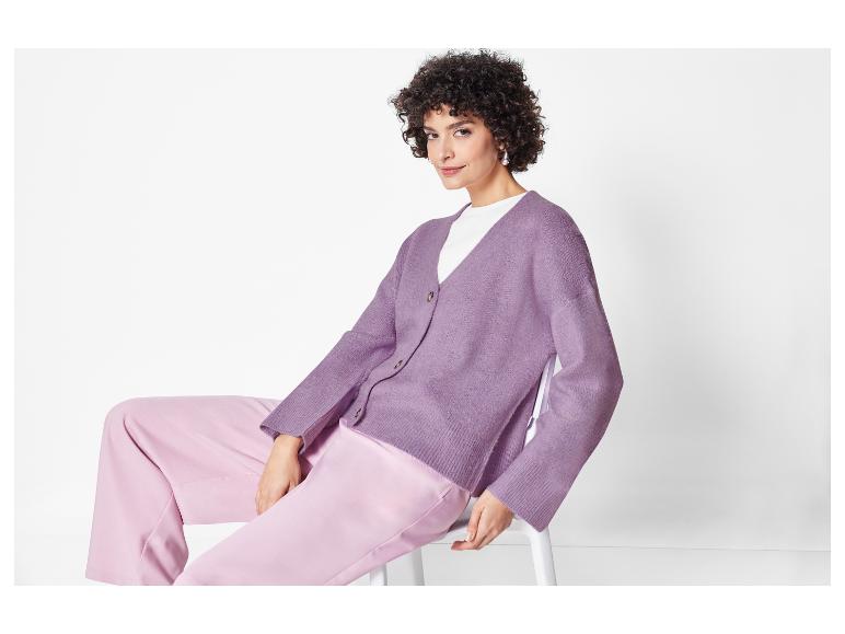Model met een paarse gebreide cardigan en roze broek.