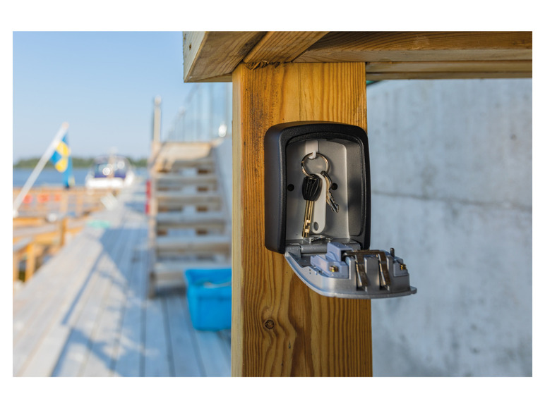 Een sleutelbox met sleutels bevestigd aan een houten paal.