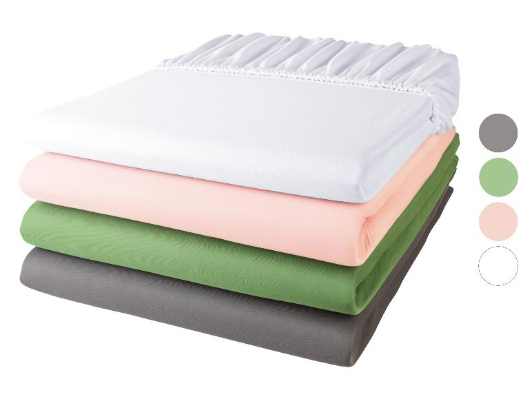 Stapel hoeslakens: wit, roze, groen en grijs.