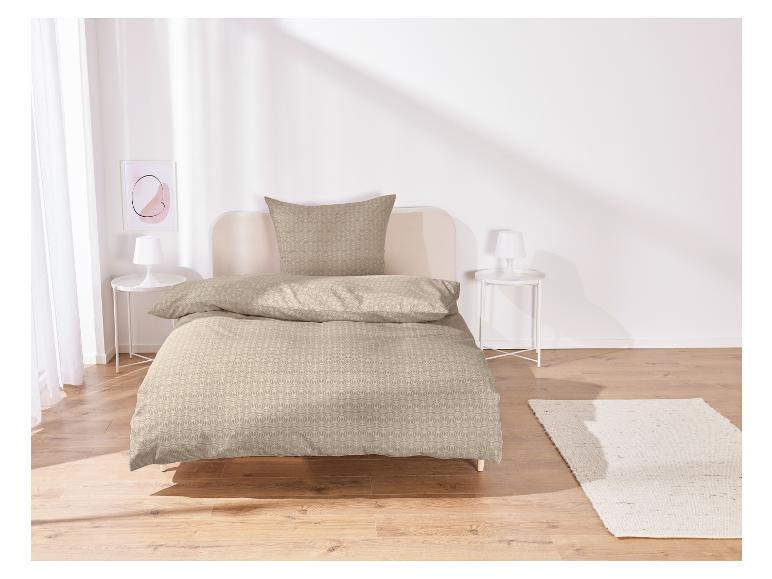 Beige dekbedovertrek met bloemenpatroon op een bed.