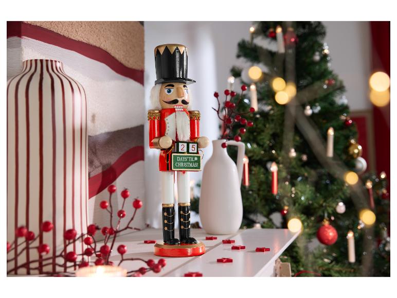 Notenkrakerbeeldje met een kerstaftelbordje op een schoorsteenmantel.