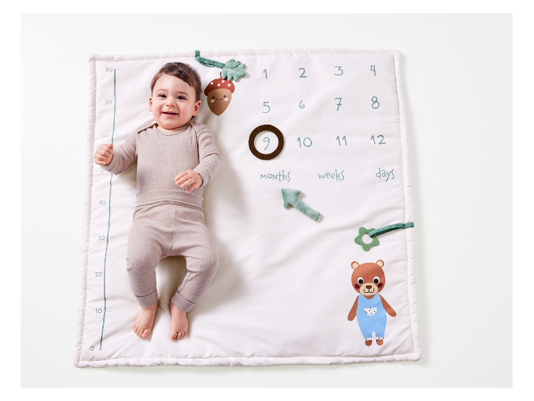 Een baby ligt op een speelmat met ingebouwde lengtemeting en bosmotieven.