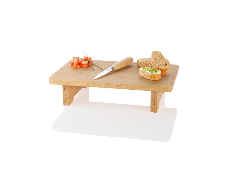 Bamboe snijplank met brood, tomaten en mes.