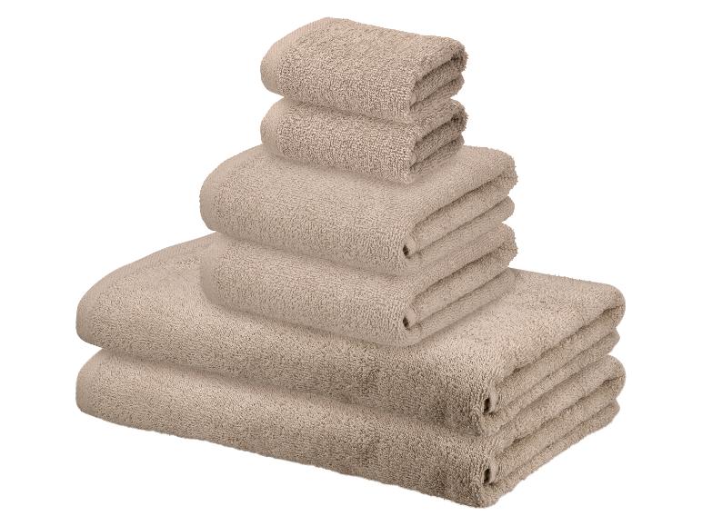 Stapel beige handdoeken in verschillende maten.