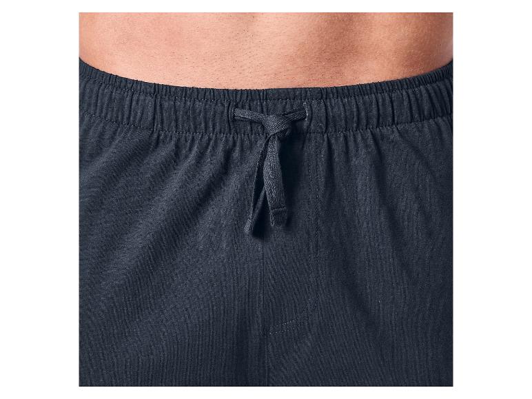 Close-up van een mannenlichaam met een donkerblauwe joggingbroek met trekkoord.