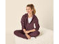 Vrouw in paarse hoodie en joggingbroek, zittend en lachend.