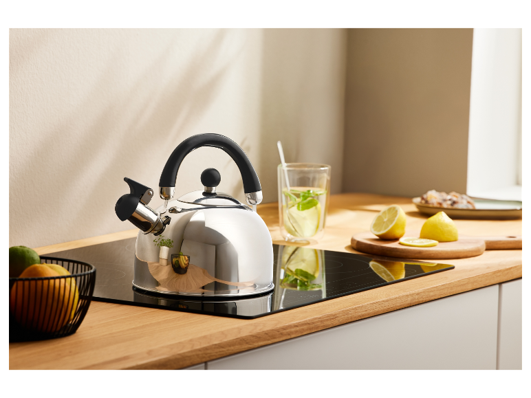 RVS waterkoker met zwarte handgreep op een inductiekookplaat in een keuken.