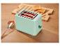 Mintgroene broodrooster met toast en jam op een houten tafel.