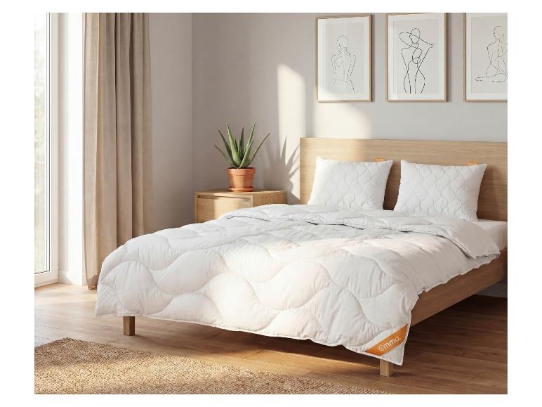 Slaapkamer met bed, wit dekbed en kussens, nachtkastje met plant.