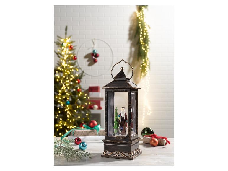 Kerstlantaarn met kerstman en kerstboom op de achtergrond