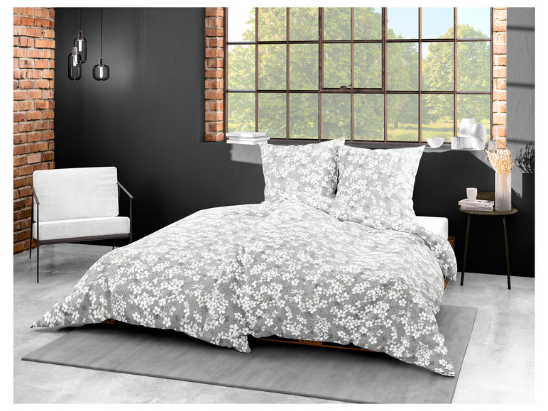 Een grijs beddengoed met witte bloemenprint, inclusief kussenslopen.