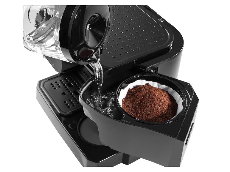 Water in een koffiezetapparaat gieten met gemalen koffie in het filter.