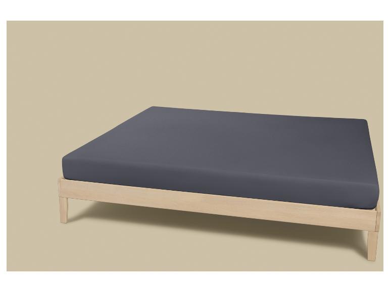 Houten bed met donkergrijs matras op een beige achtergrond.