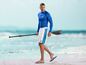 Man met paddleboard uitrusting, inclusief Mi-shirt, shorts en peddel