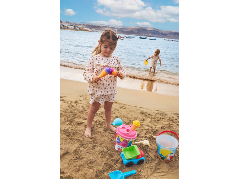 Kinderen spelen op het strand met zandspeelgoed, emmers en schepjes.