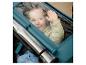 Lachend kind in een kinderwagen met transparante hoes, zwaaiend met de hand.