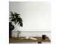 Houten bureau met open boek, mok, vaas met plant en Grieks patroon op de muur.