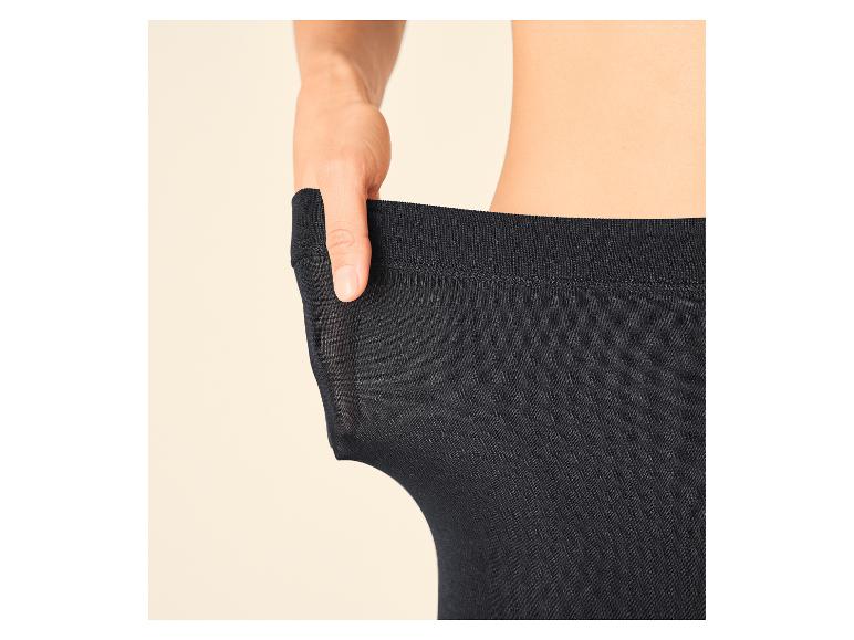Vrouwenhand trekt aan zwarte panty om de elasticiteit te tonen.