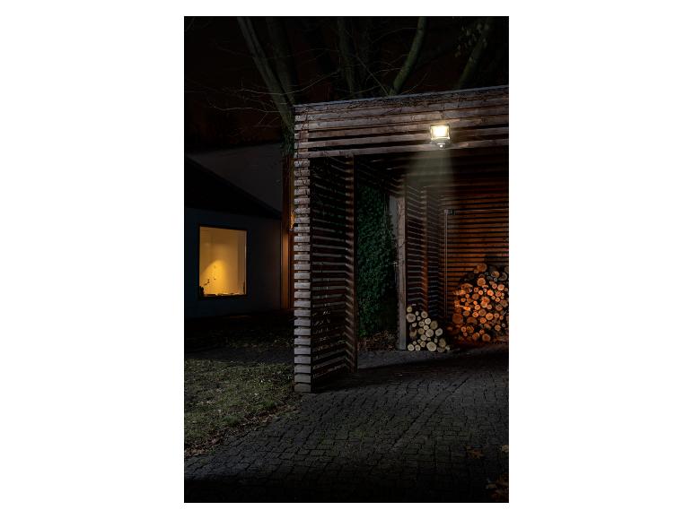 Buitenverlichting met bewegingssensor boven een houten afdak met brandhout.