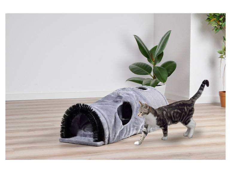 Een kat speelt met een grijs kattenhol met een borstel.
