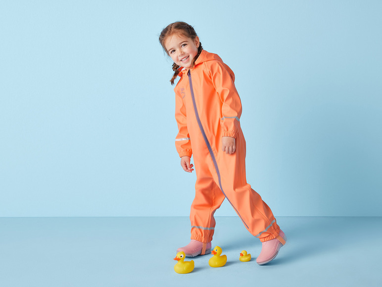 Een kind in een oranje regenpak en roze laarzen loopt met rubberen eendjes.
