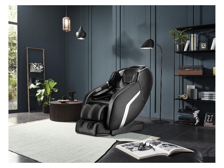 Zwarte massagestoel in een moderne kamer met boekenplank en planten.