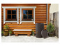 Een houten regenwaterton naast een houten bankje voor een houten huis.